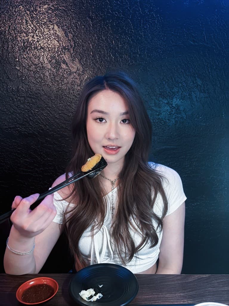 Helen Li at dinner holding sushi with chopsticks