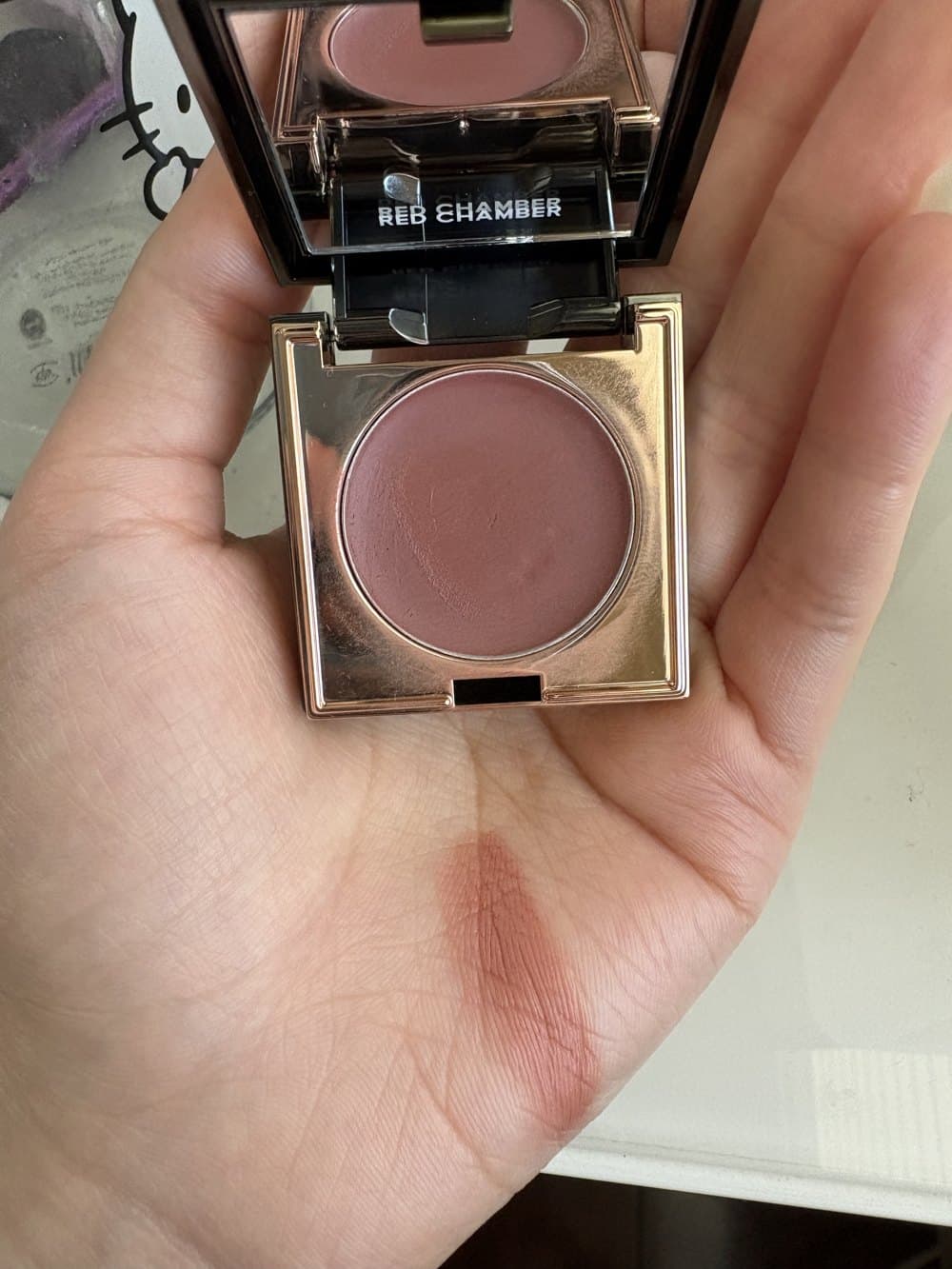 A rose-gold blush compact and swatch of the shade on Helen's palm
