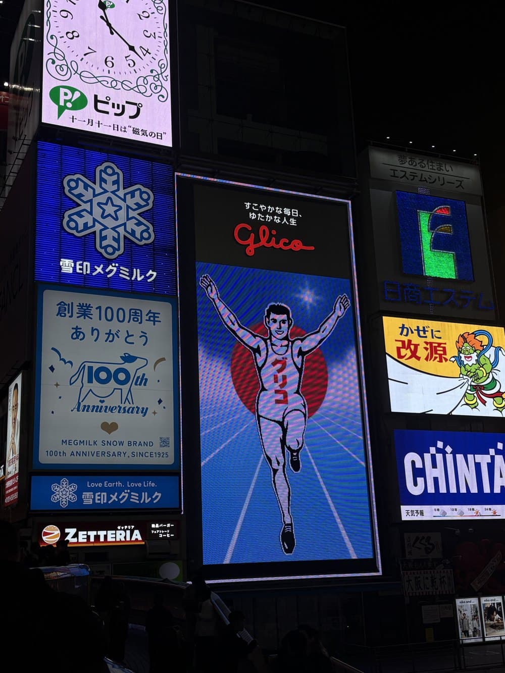 The Glico running man billboard lit up over Dotonbori in Osaka at night